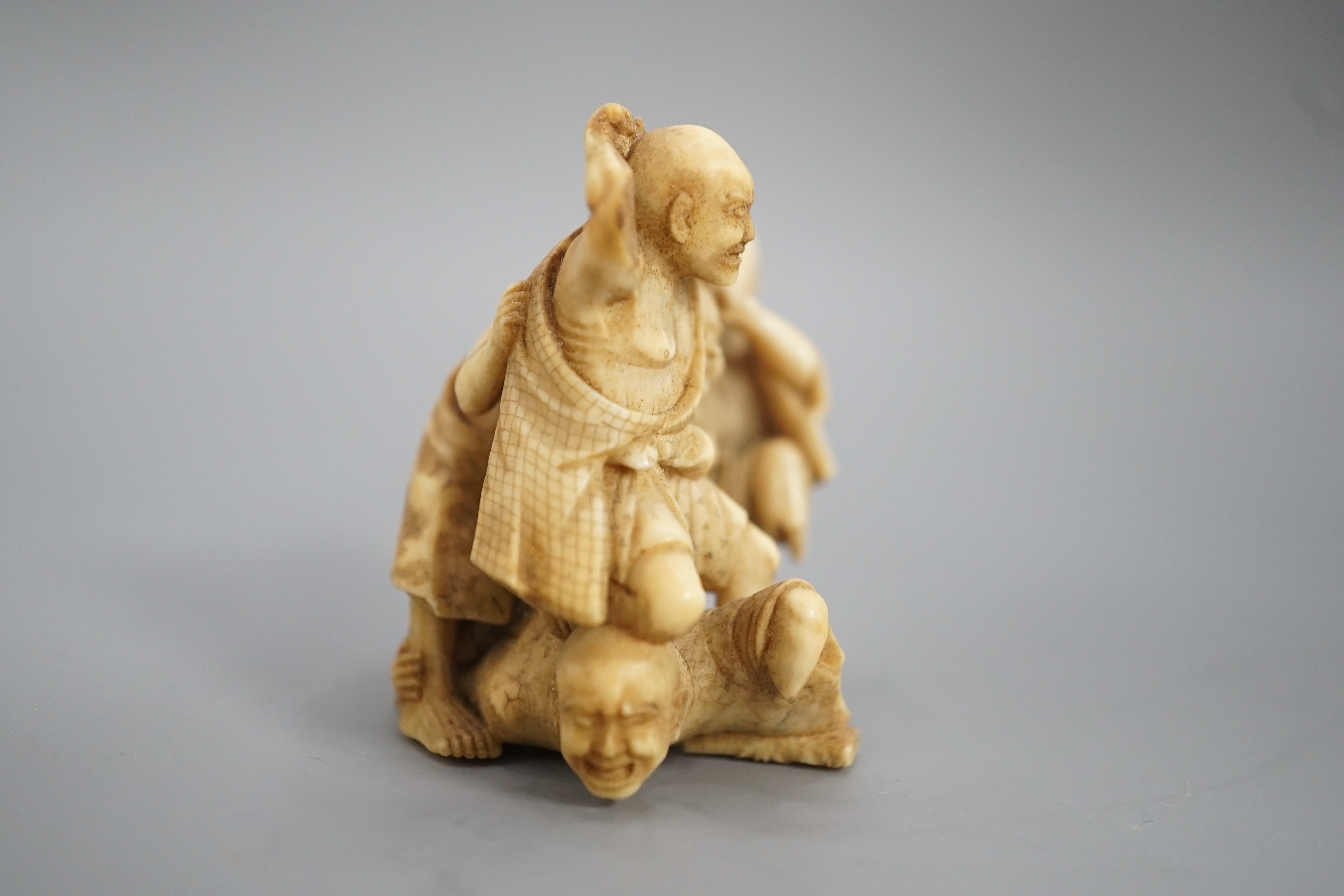 A Japanese ivory group of four men fighting, signed, Meiji period, 5.5cm